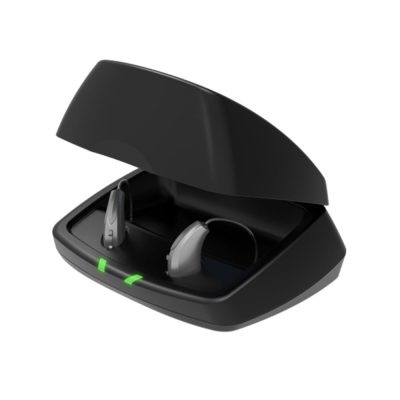 A pair of gray hearing aids sit in an open Starkey Standard Charger with two green front indicator lights, displayed on a white background.